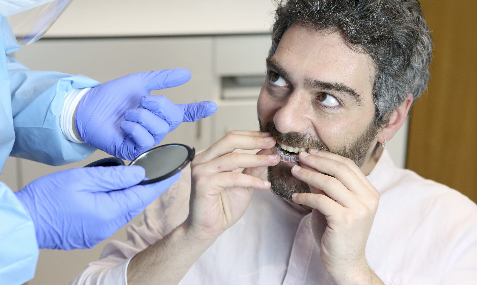 Paciente poniéndose la funda transparente en los dientes