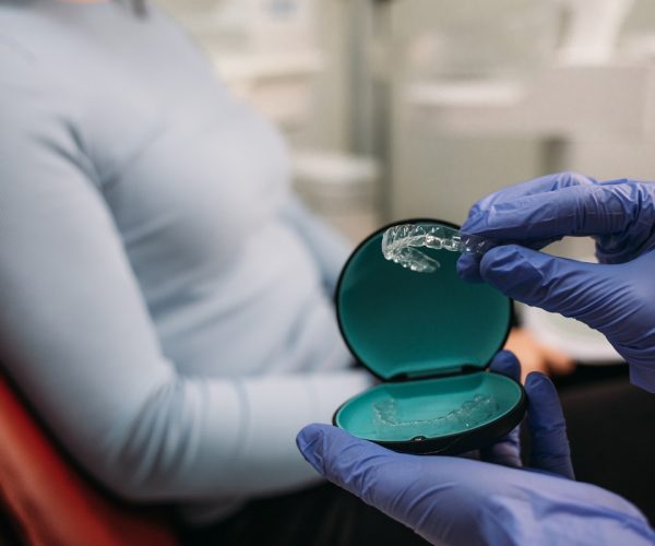 Female doctor explaining orthodontics retainer to patient in exam room